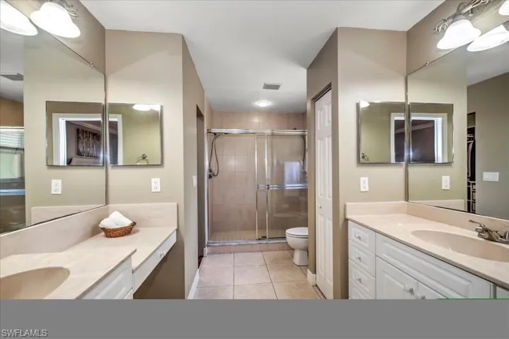 Bathroom featuring a shower with door, tile flooring, toilet, and vanity