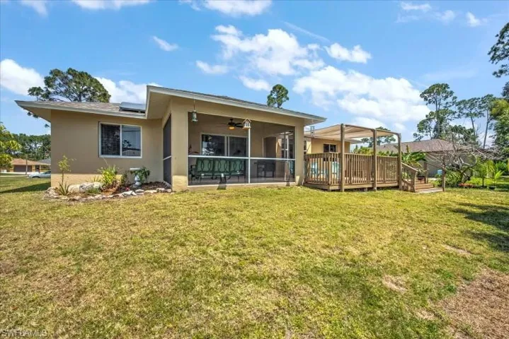 Back of property featuring a yard, ceiling fan, and a wooden deck
