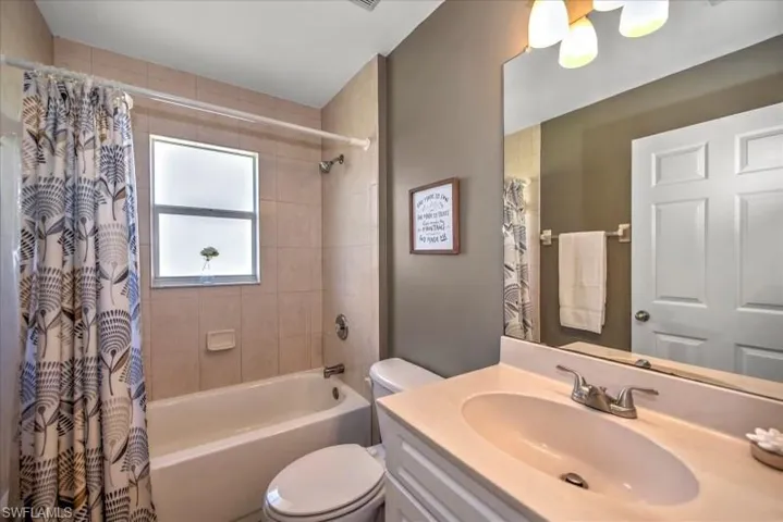 Full bathroom featuring shower / bathtub combination with curtain, toilet, and vanity