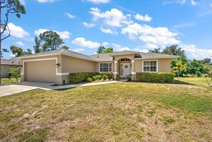 Ranch-style home featuring a garage and a front lawn