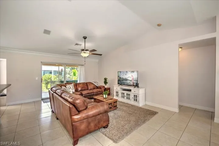 Tiled living room featuring vaulted ceiling and ceiling fan