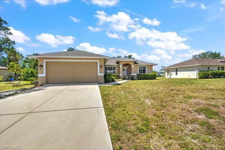 Ranch-style house with a garage and a front lawn