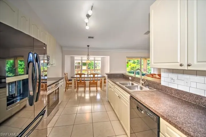 Kitchen featuring black appliances, pendant lighting, sink, track lighting, and light tile floors