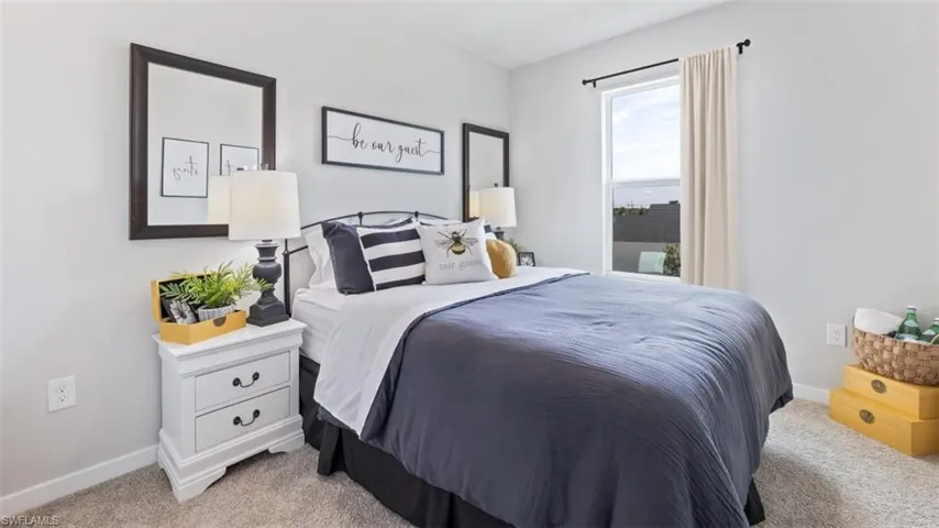 Model home. Bedroom with baseboards and light colored carpet
