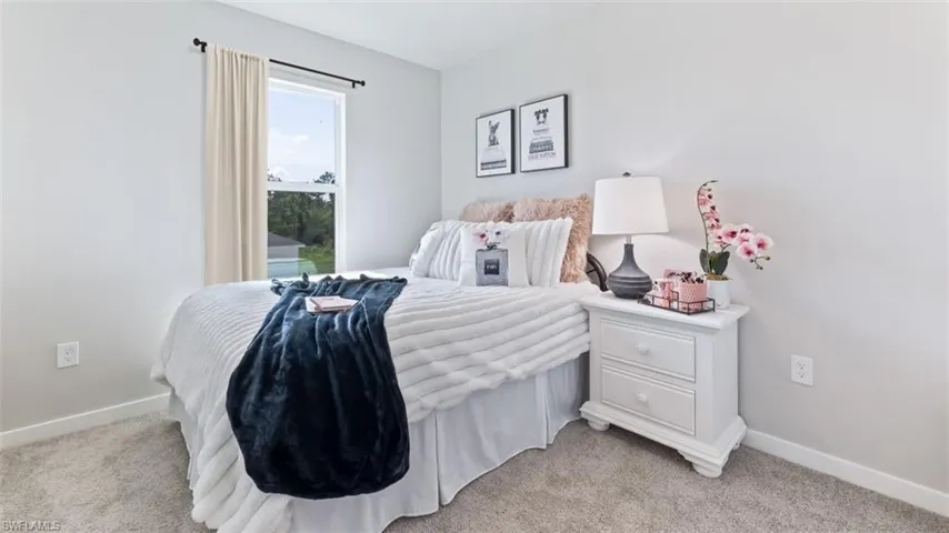 Model home. Bedroom featuring baseboards and light carpet