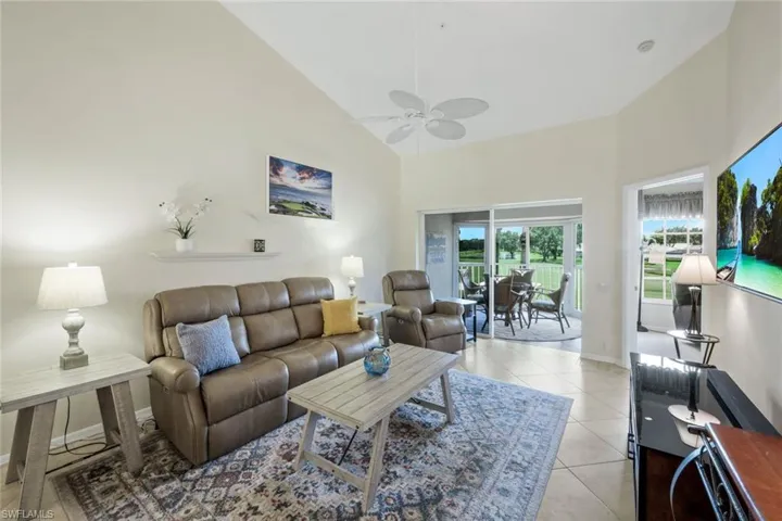 Living area featuring Reclining Couch, Chair, Roomba, light tile patterned flooring, high vaulted ceiling, and a ceiling fan