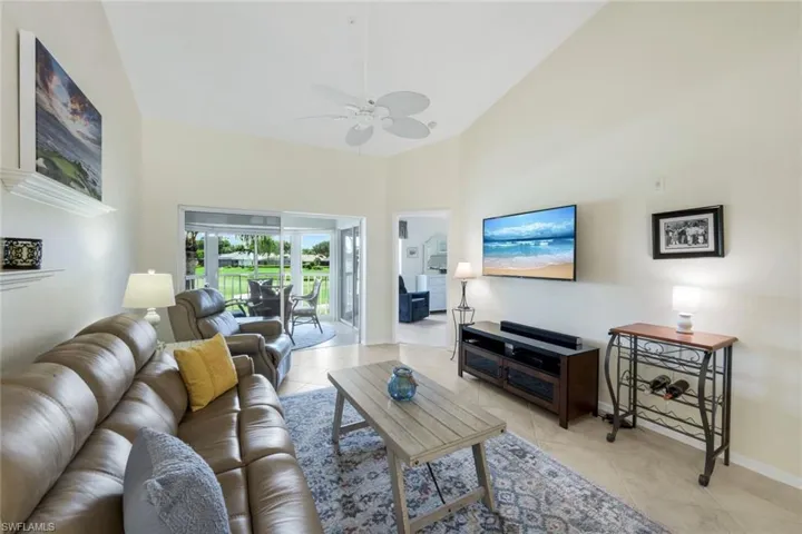 Living area featuring Reclining Couch, Chair, Roomba, light tile patterned flooring, high vaulted ceiling, and a ceiling fan