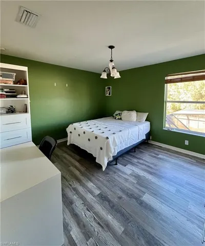 Bedroom with dark wood finished floors and baseboards