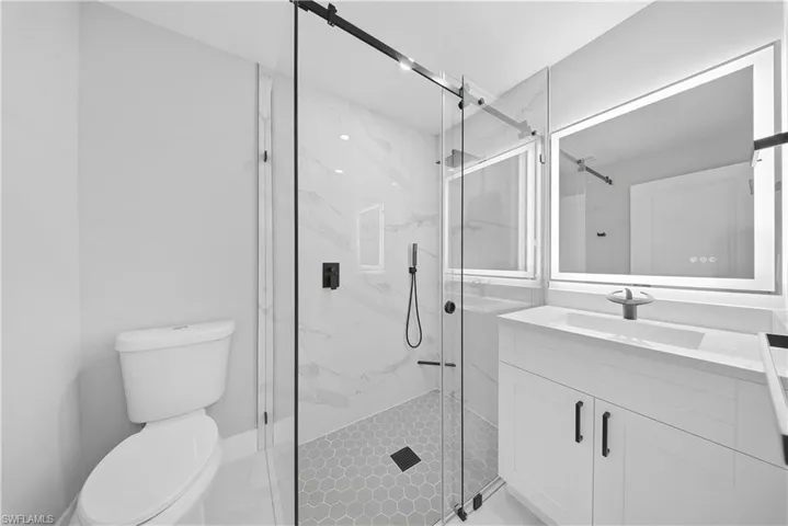 Bathroom featuring vanity and a marble finish shower