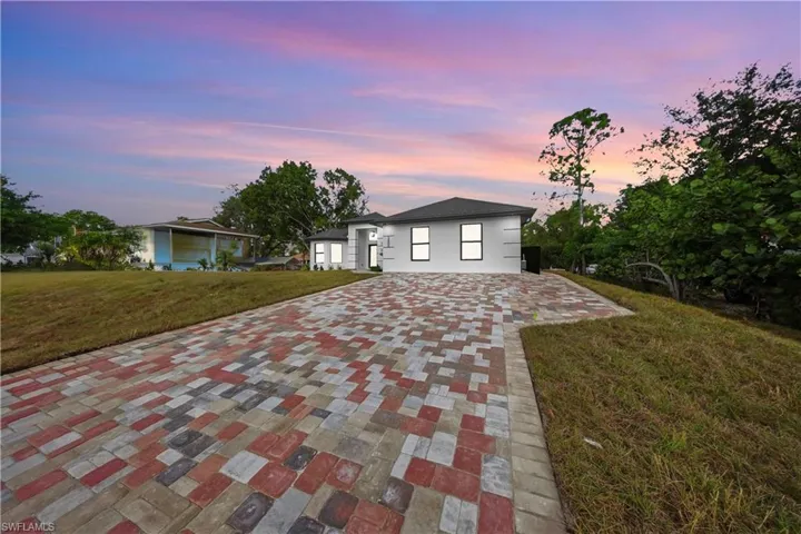 View of front of property with a front lawn and decorative driveway