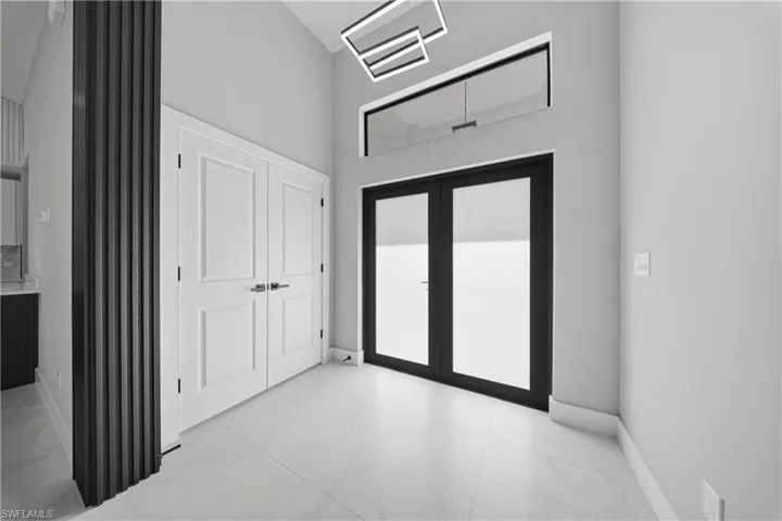 Entryway featuring light marble finish floors, a high ceiling, and french doors
