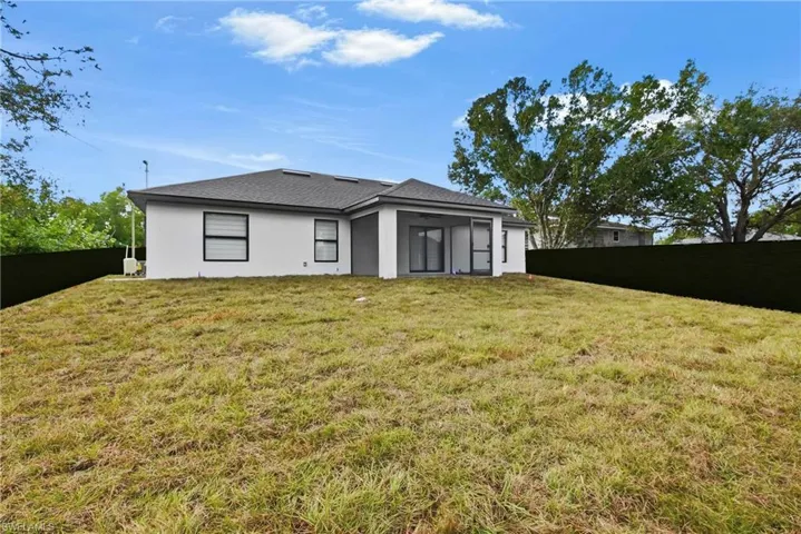 Rear view of property featuring a fenced backyard, a sunroom, and stucco siding