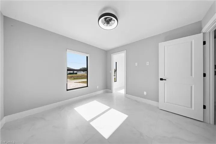 Unfurnished bedroom featuring light marble finish floors and baseboards