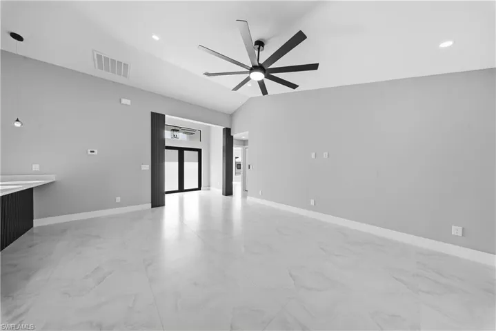 Empty room with light marble finish flooring, recessed lighting, lofted ceiling, and ceiling fan