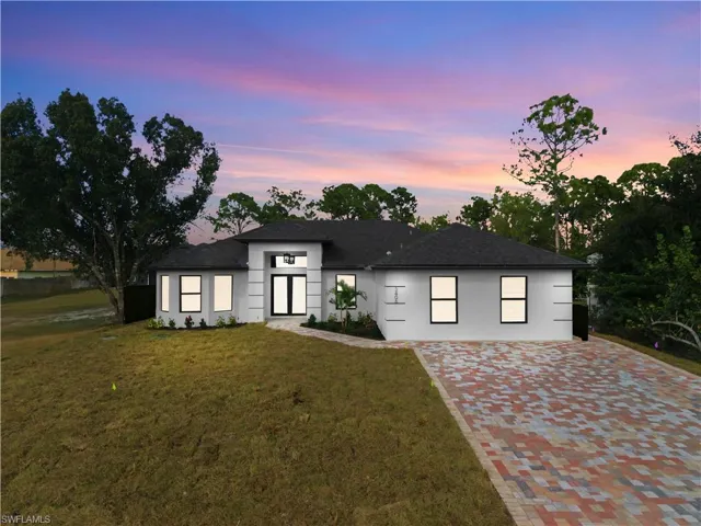 View of front of property featuring a yard, stucco siding, and driveway