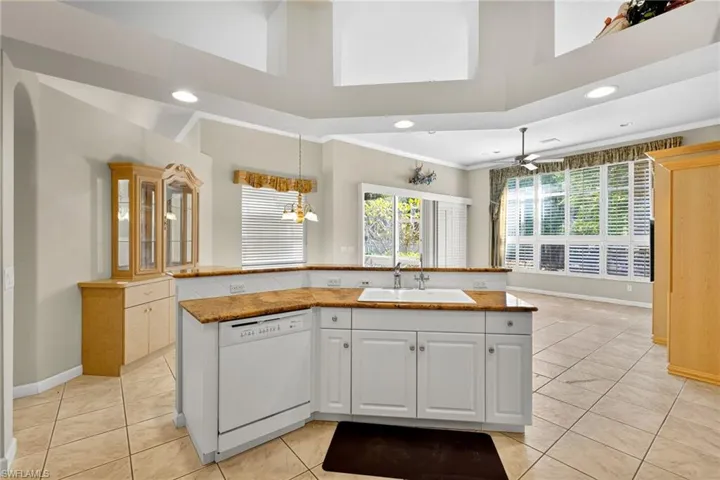 Kitchen featuring an island with sink, crown molding, white dishwasher, light tile patterned flooring, and recessed lighting