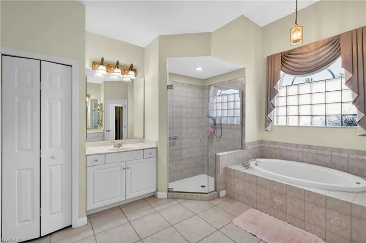 Full bathroom with vanity, a closet, a garden tub, light tile patterned floors, and a shower stall