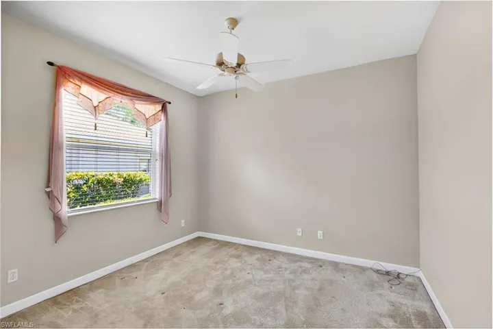 Carpeted empty room featuring baseboards and a ceiling fan