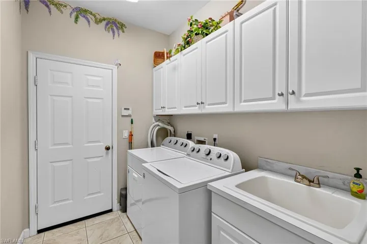 Washroom featuring light tile patterned floors, cabinet space, and washer and dryer