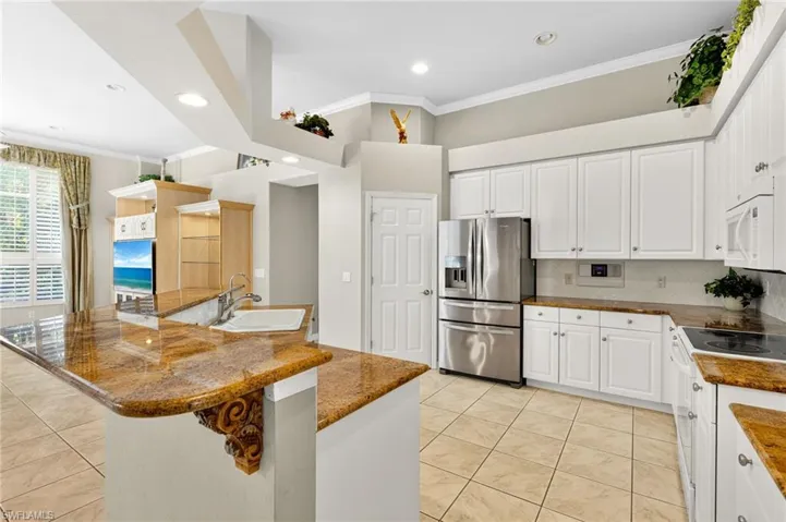 Kitchen with crown molding, white appliances, backsplash, white cabinets, and recessed lighting