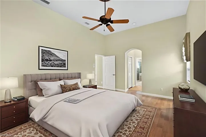 Bedroom with wood finished floors, ceiling fan, and arched walkways