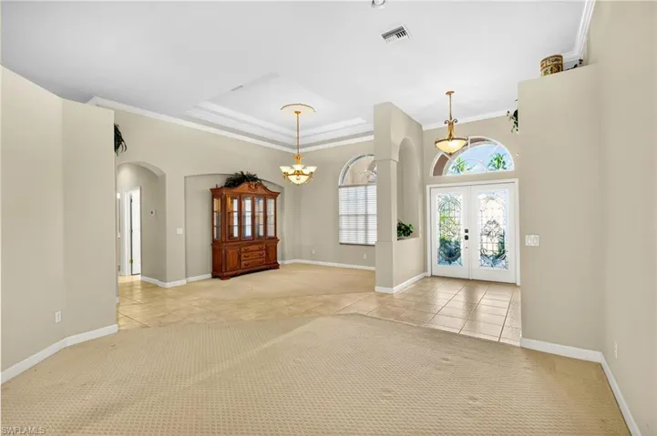 Foyer entrance featuring crown molding, light carpet, arched walkways, and light tile patterned flooring
