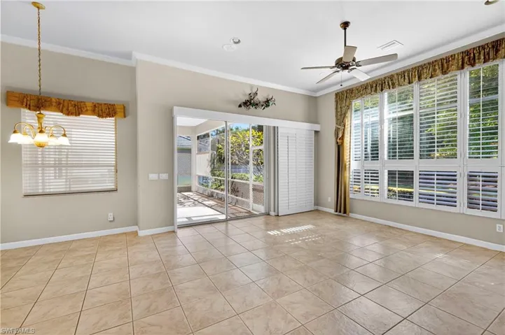 Spare room featuring ornamental molding, healthy amount of natural light, a chandelier, light tile patterned floors, and ceiling fan