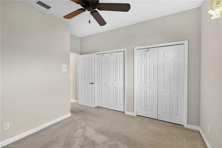 Unfurnished bedroom featuring two closets, light carpet, and ceiling fan