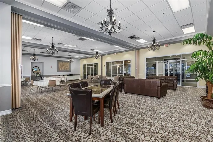 Carpeted dining space featuring a chandelier and a paneled ceiling