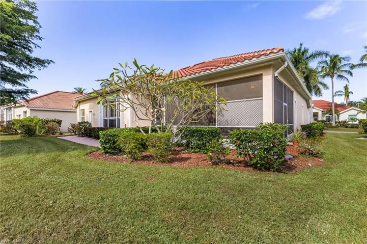 Rear view of house with a lawn, a tiled roof, a sunroom, and stucco siding