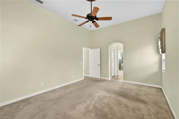 Spare room featuring carpet flooring, arched walkways, and a ceiling fan