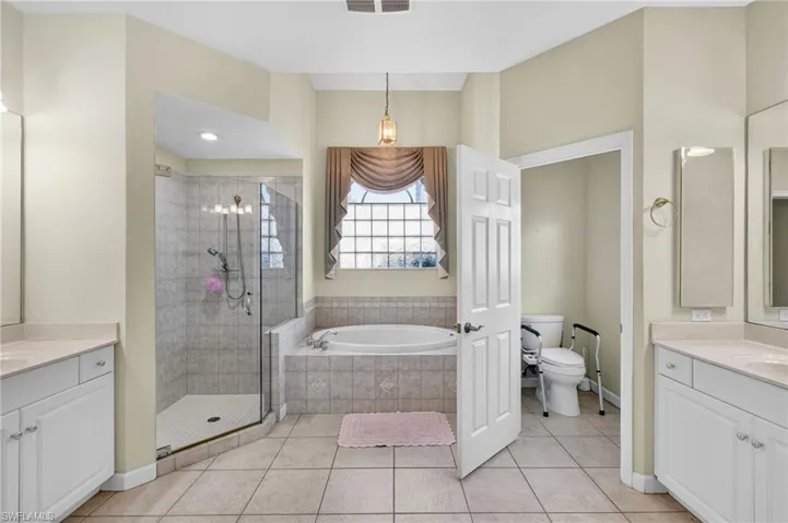 Bathroom with two vanities, a stall shower, light tile patterned floors, and a garden tub