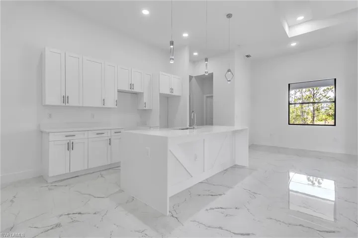 Kitchen featuring light marble finish floors, white cabinetry, recessed lighting, hanging light fixtures, and light countertops