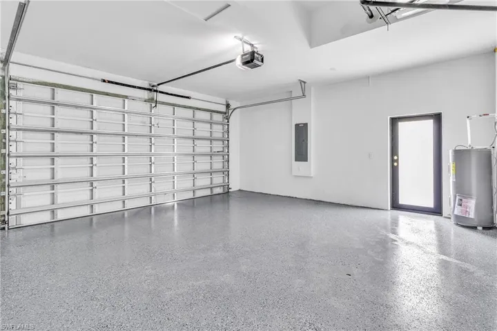 Garage with water heater, electric panel, and a garage door opener