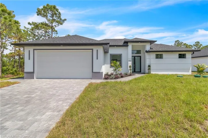 Prairie-style home featuring stucco siding, decorative driveway, an attached garage, and a front yard