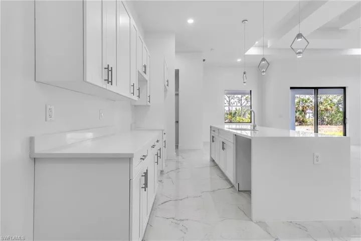 Kitchen with light marble finish flooring, white cabinets, light countertops, decorative light fixtures, and recessed lighting