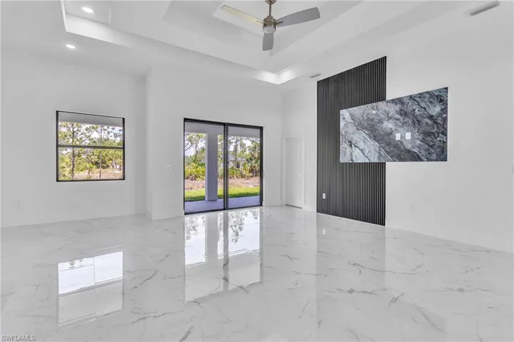 Unfurnished room featuring marble tiled flooring, a raised ceiling, and ceiling fan