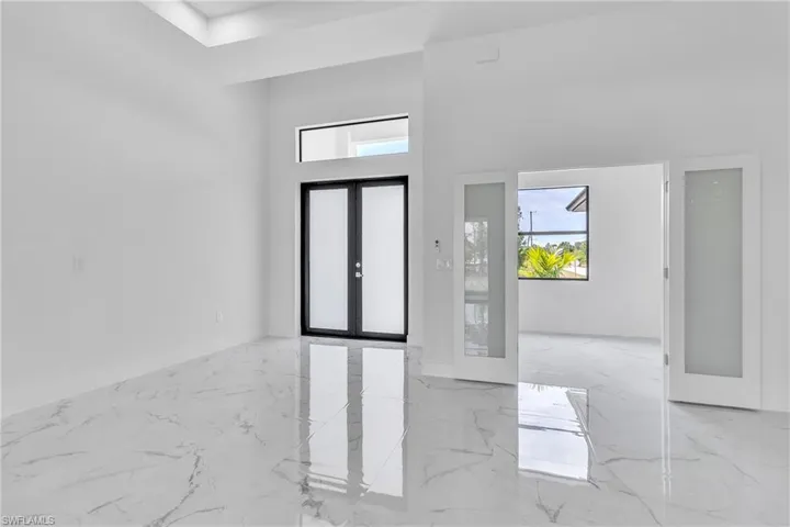 Foyer entrance with french doors, marble tiled flooring, a high ceiling, and healthy amount of natural light