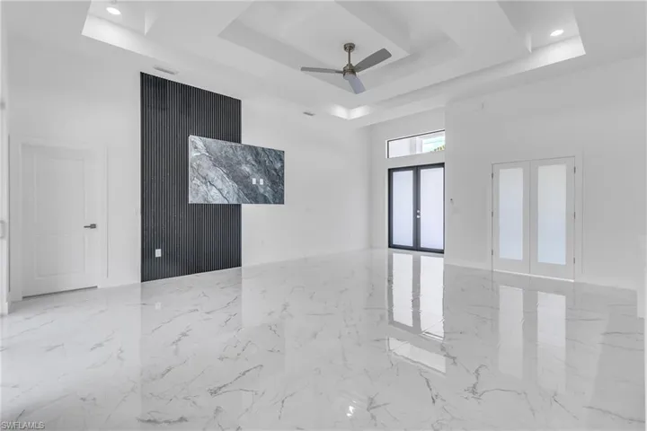 Spare room with a raised ceiling, french doors, marble tiled floors, a ceiling fan, and a high ceiling