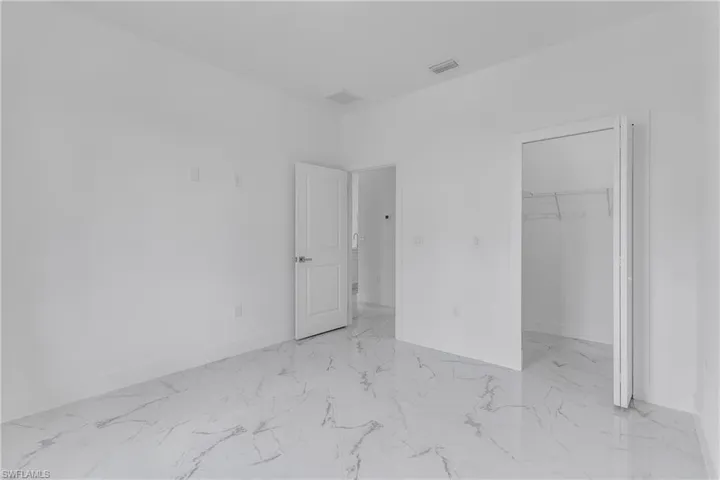 Unfurnished bedroom with marble look tiles and a walk in closet