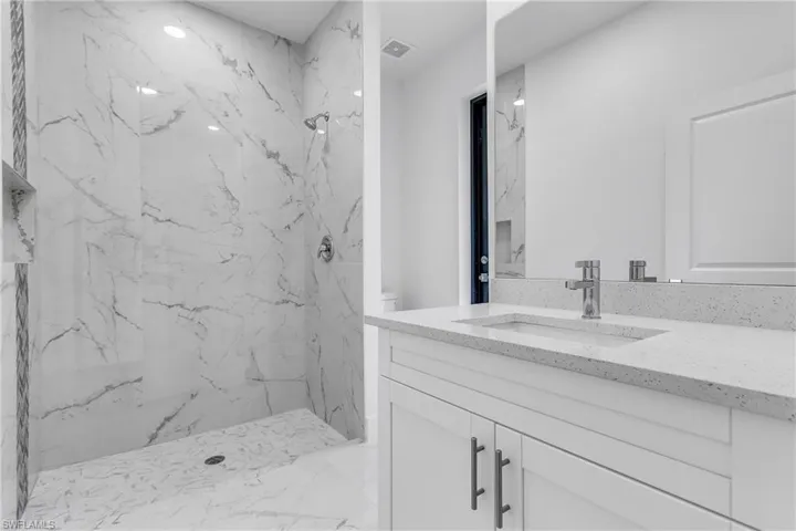 Bathroom with vanity, a marble finish shower, and marble finish floors