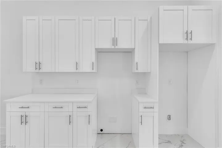 Kitchen featuring light marble finish flooring, light countertops, and white cabinetry