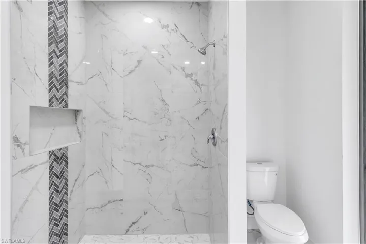 Full bath with a marble finish shower