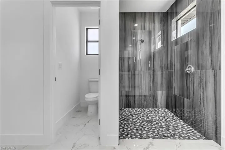 Full bathroom with marble finish flooring, walk in shower, and healthy amount of natural light