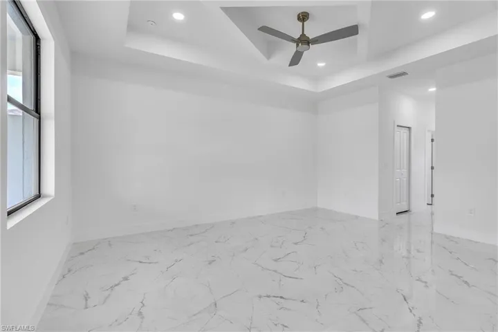 Spare room with marble finish floors, recessed lighting, a raised ceiling, and a ceiling fan