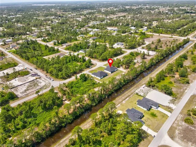 Aerial view of property and surrounding area featuring a large body of water and a tree filled landscape
