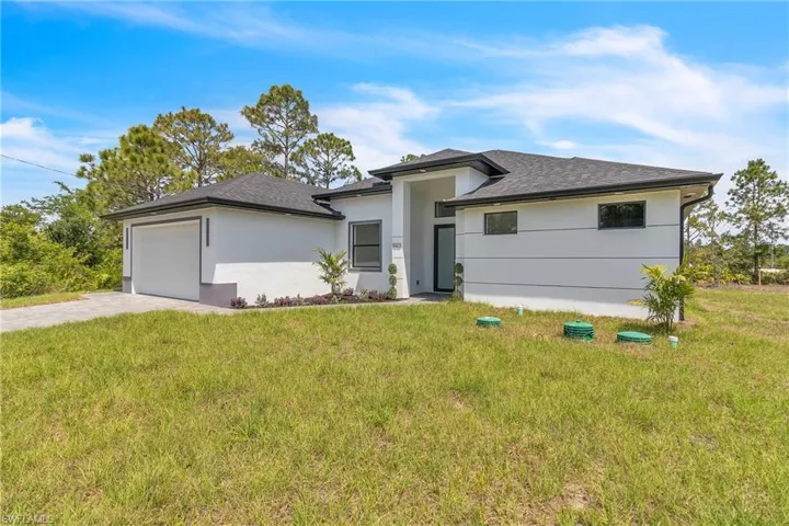 Prairie-style home with a garage, driveway, a front lawn, and stucco siding