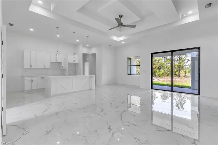 Unfurnished living room featuring recessed lighting, a raised ceiling, light marble finish flooring, and a ceiling fan
