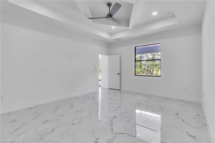 Spare room with light marble finish floors, a tray ceiling, a ceiling fan, and recessed lighting