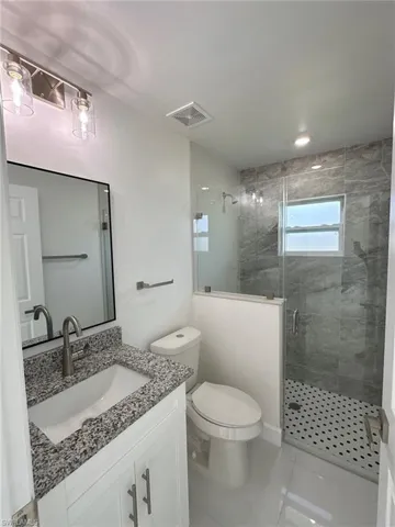 Bathroom featuring vanity, toilet, a shower with shower door, and tile patterned flooring